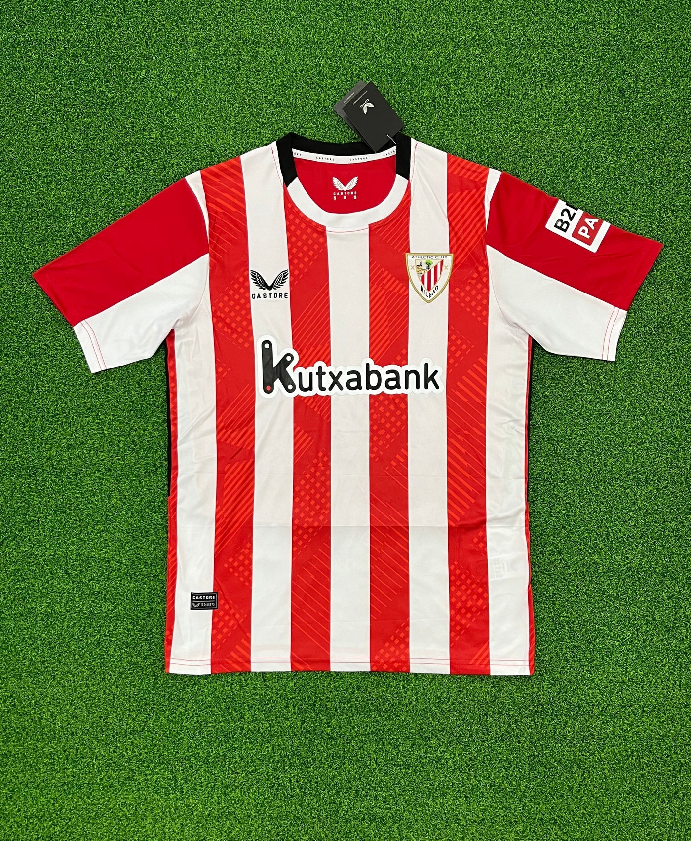 a red and white soccer jersey sitting on top of a green field