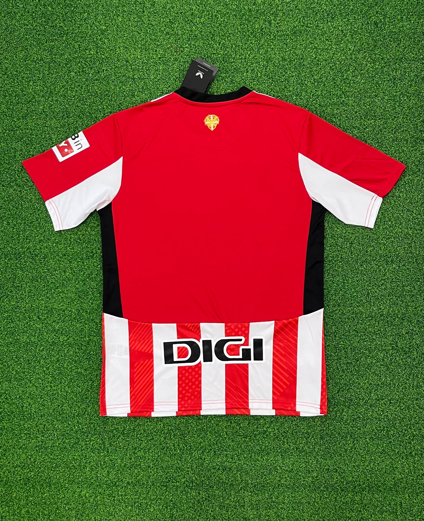 a red and white shirt sitting on top of a green field