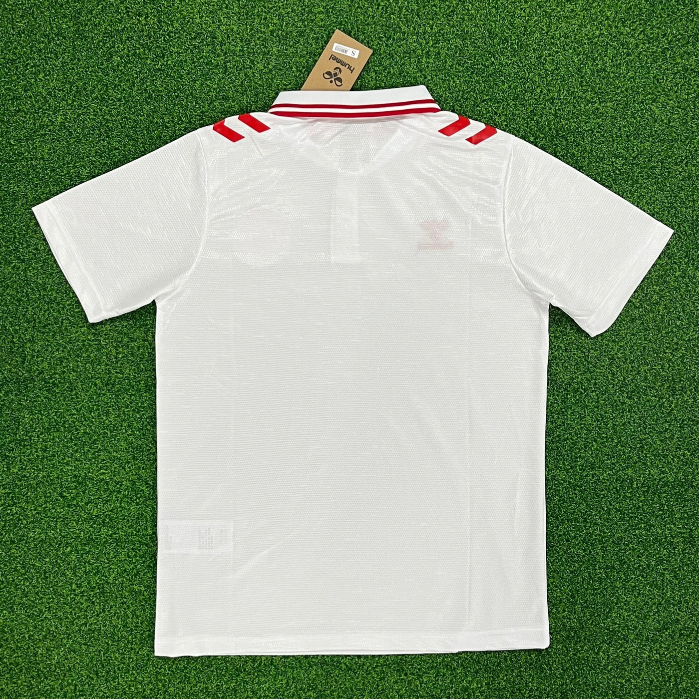 a white polo shirt laying on top of a green field