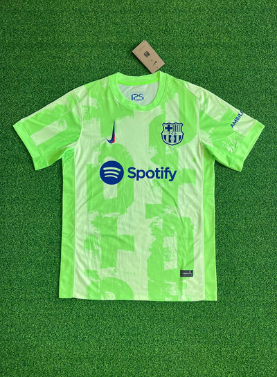 a green soccer jersey sitting on top of a green field