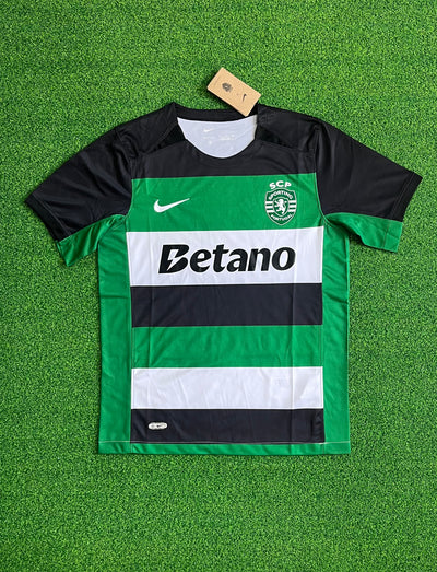 a green and black soccer jersey laying on the ground