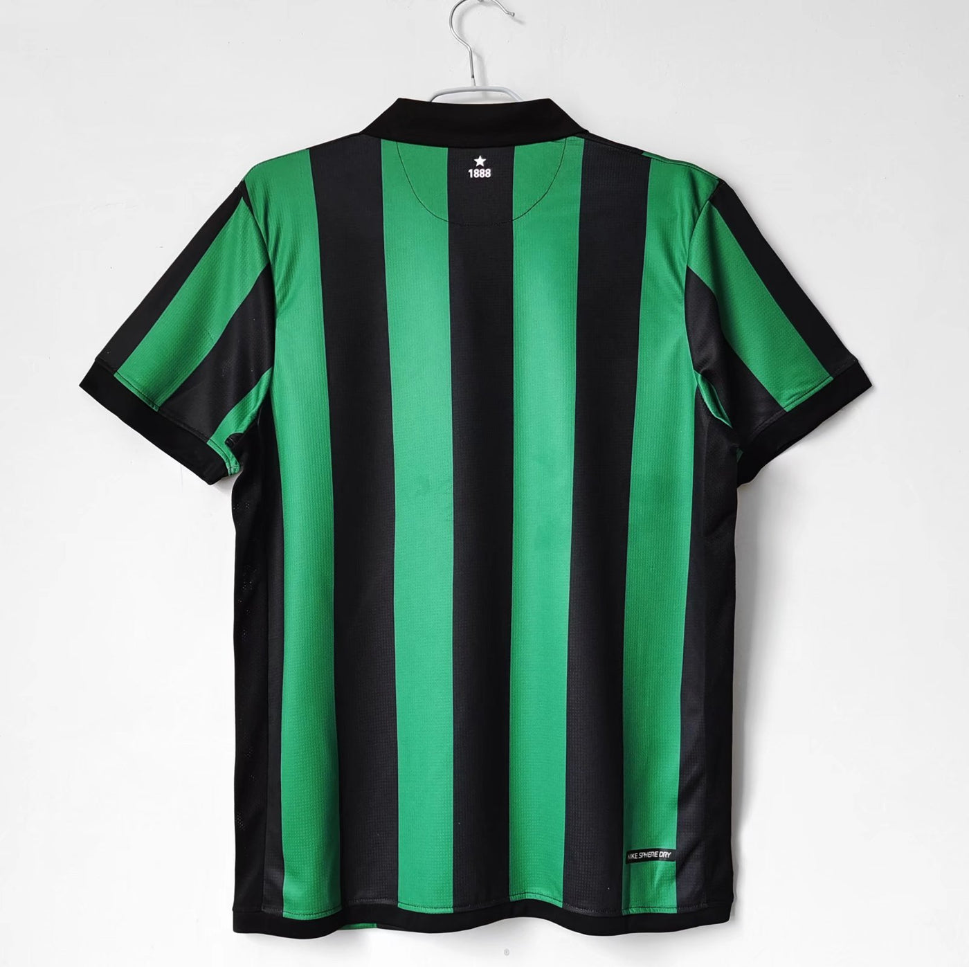 a green and black soccer jersey hanging on a hanger