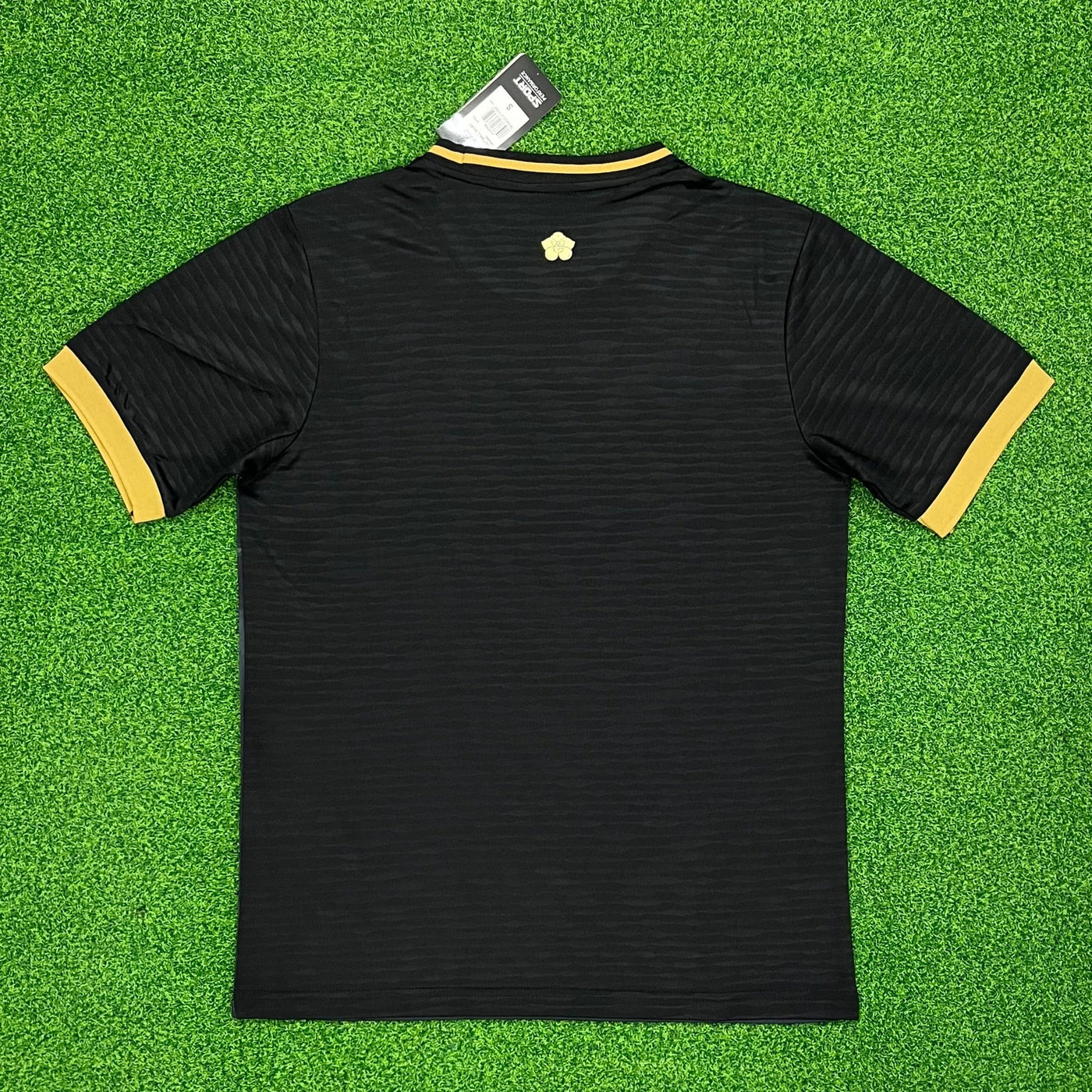 a black and yellow shirt laying on top of a green field