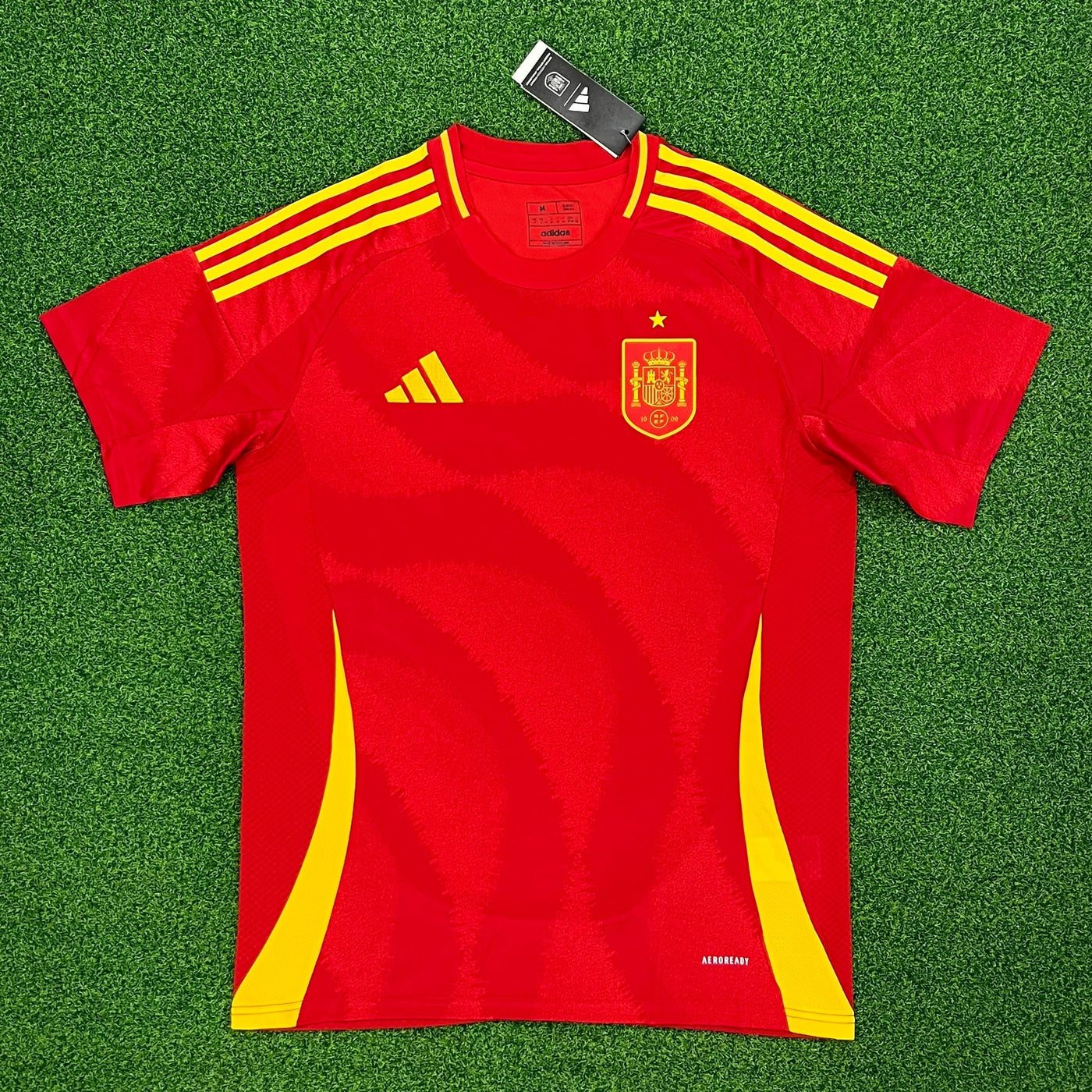 a red and yellow soccer jersey laying on a green field