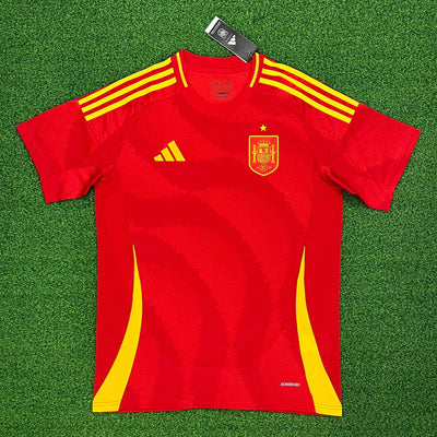 a red and yellow soccer jersey laying on a green field