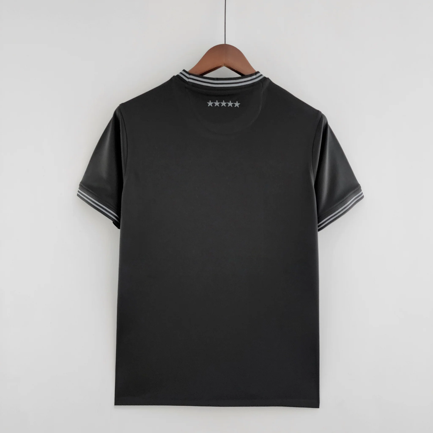 a black t - shirt hanging on a wooden hanger